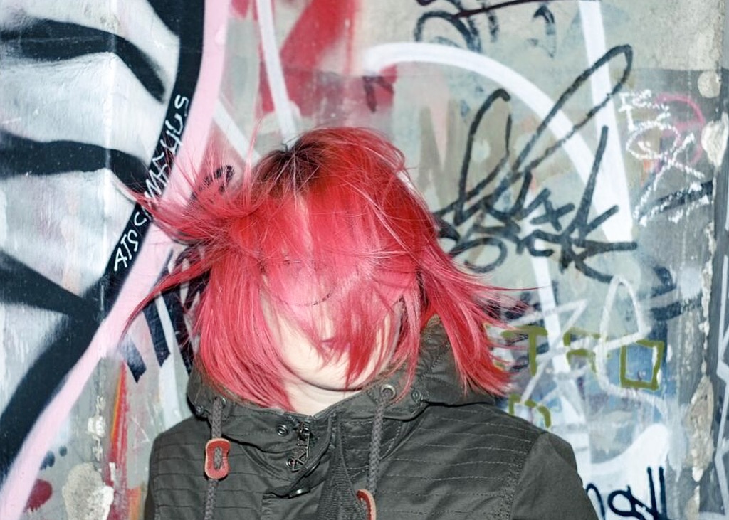 Frau mit pinken Haaren wird vor einer Graffiti Wand in Berlin fotografiert