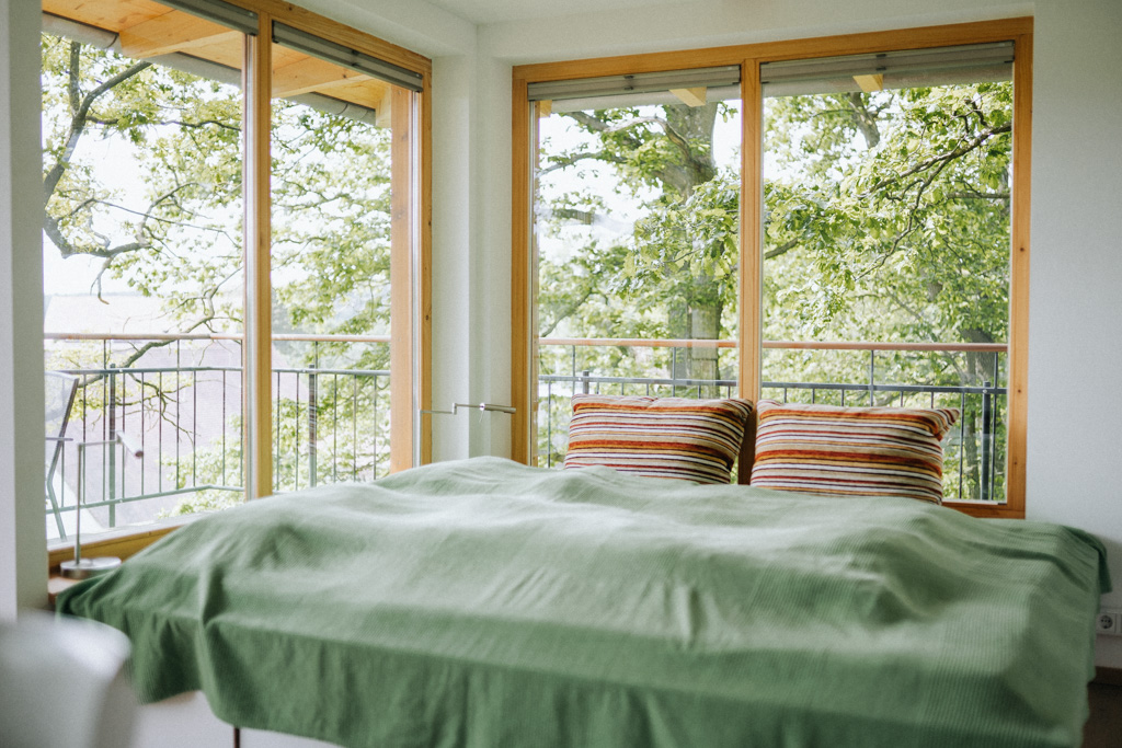 Übernachten im Baumhaus Kuckusnest: Blick auf das Doppelbett im unteren Bereich mit Blick raus ins Grüne und auf den Bauernhof