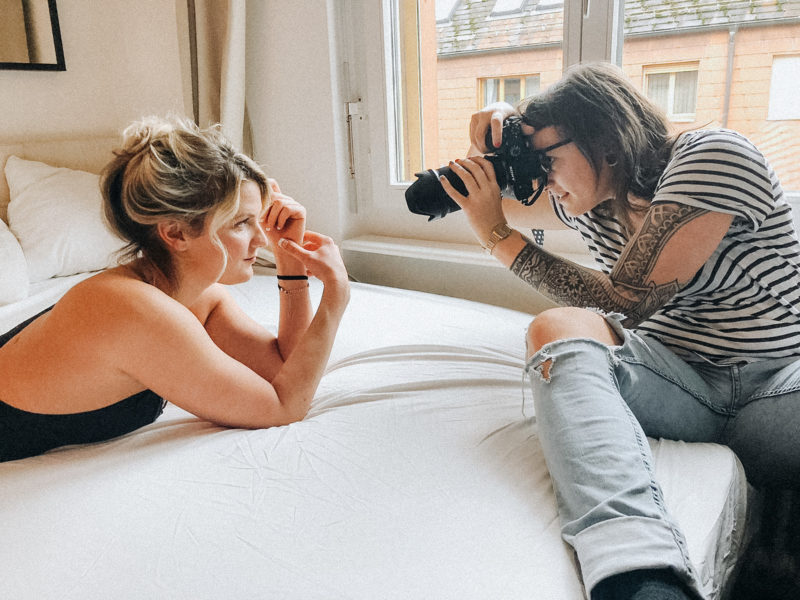 Fotografin Lisa Ludwig fotografiert Model Desiree im Bereich Boudoir mit natürlichem Licht auf einem Bett am Fenster