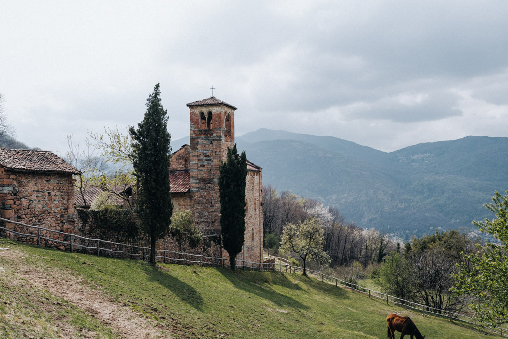 Auf der Monte San Salvatore Wanderung nach Morcote geht es vorbei an der Kirche S. Maria Assunta di Torello mit Blick auf die umliegenden Berge