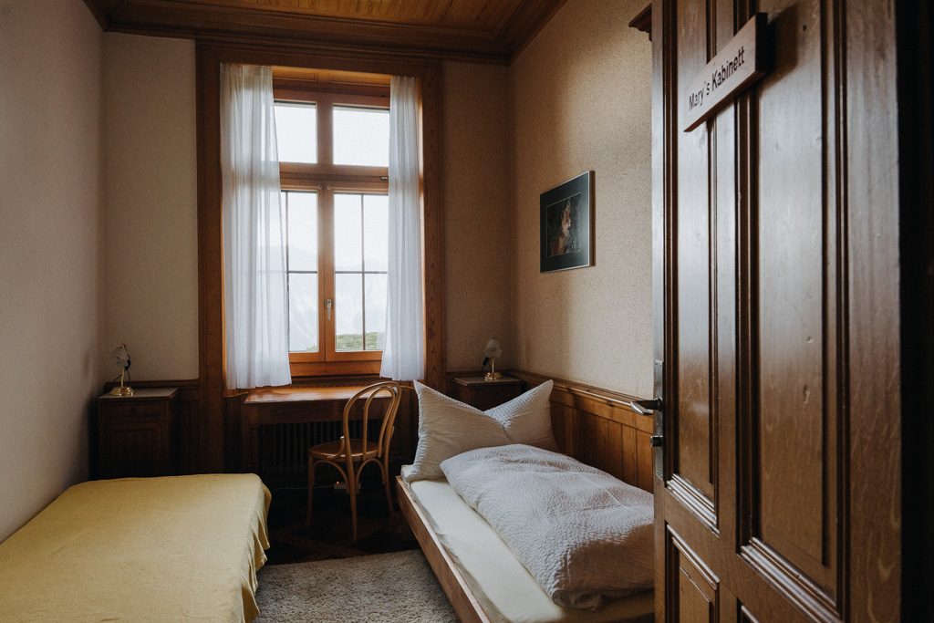 Doppelzimmer in der Villa Cassel in der Aletsch Arena im Wallis in der Schweiz mit zwei Einzelbetten, einem Schreibtisch und Stuhl