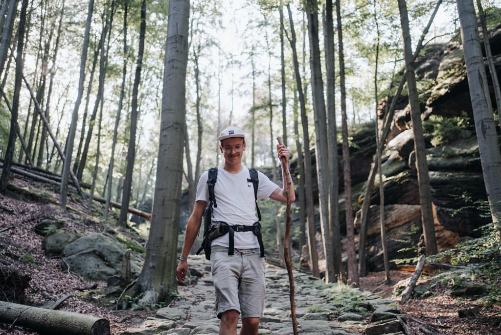 Dominic Wolf, Freund von Reisebloggerin Lisa Ludwig hat sich während der Wanderung in der Sächsischen Schweiz einen großen Wanderstock gesucht und läuft nun vom Großen Winterberg zum Heringsloch