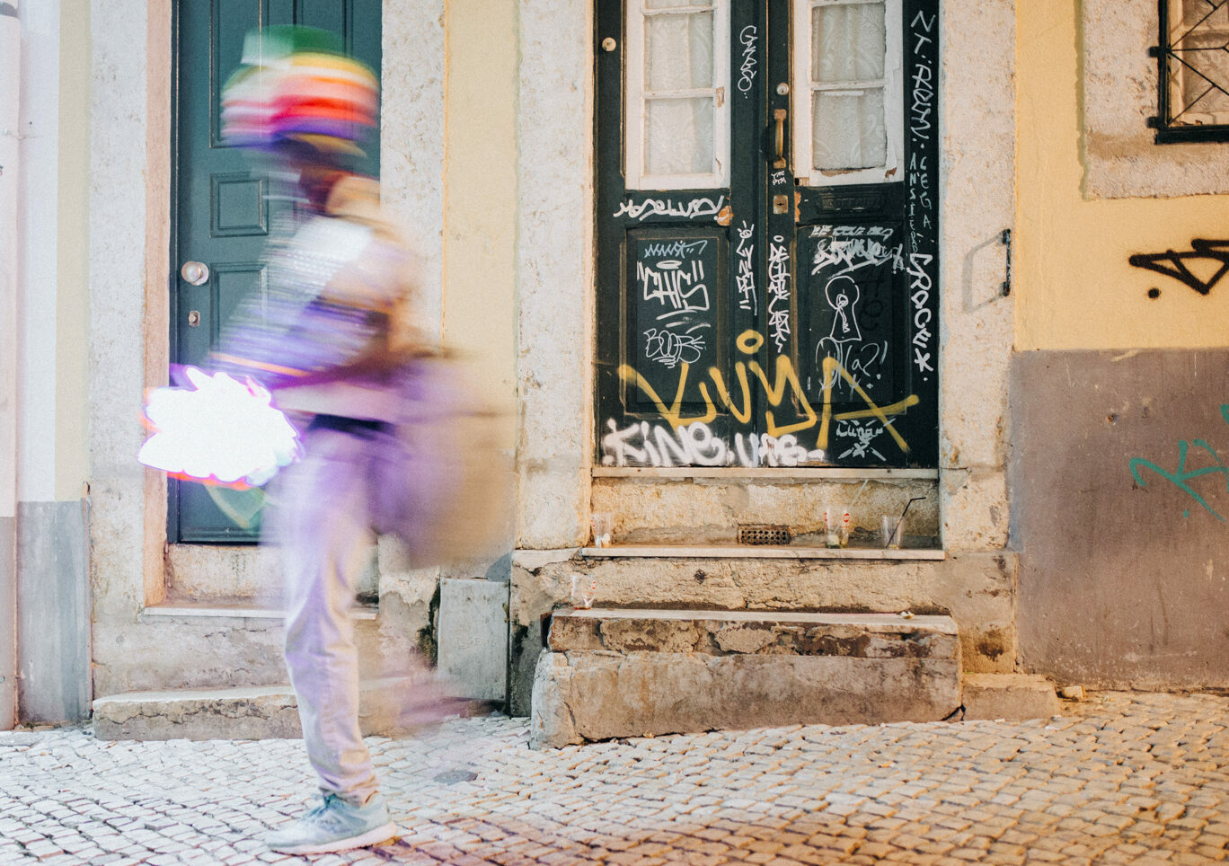 Nightlife kann auch ein Fotospot in Lissabon sein, denn das spielt sich draussen ab. Eine Tür mit Graffiti in Barro Alto mit einem bunten Strassenverkäufer
