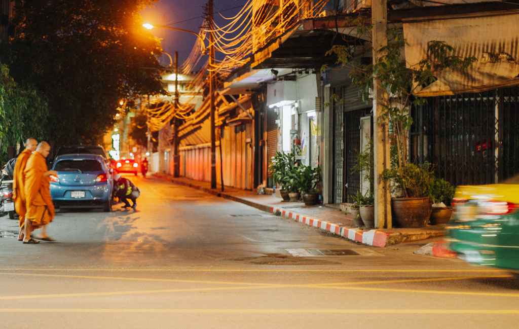 Streetfotografie Aufnahme zweier buddhistischer Mönche, die am Abend durch die Strassen von Bangkok laufen