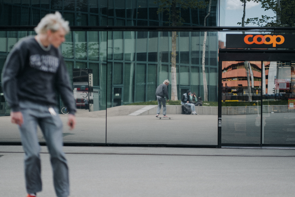 Streetfotografie an einem öffentlichen Platz in Zürich mit Lisa Ludwig in der Spiegelung des Prime Tower in Zürich