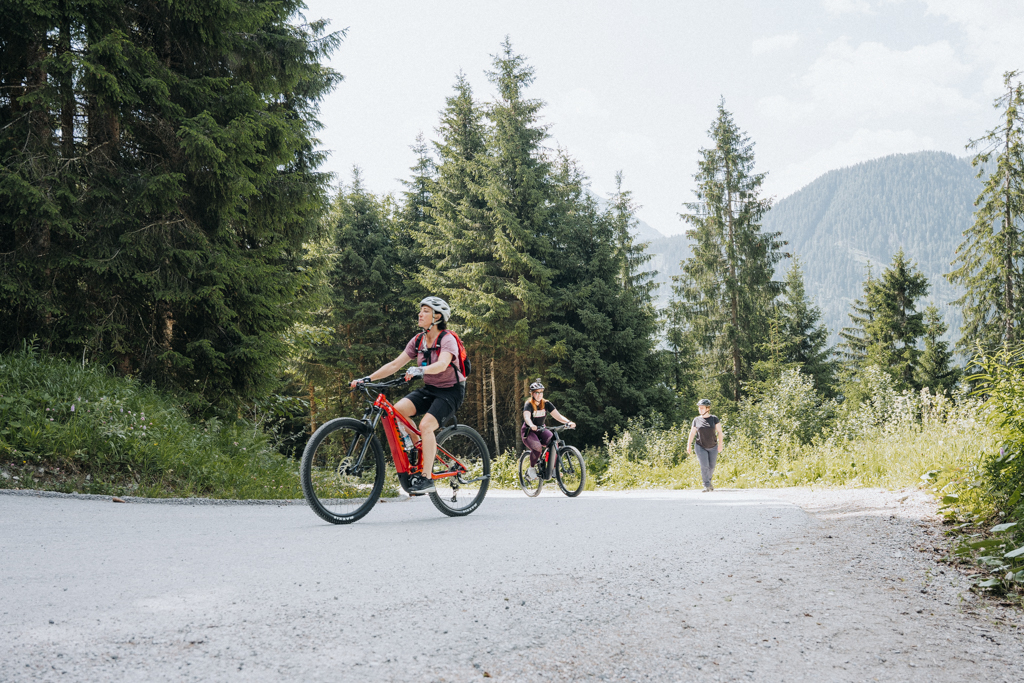 Zillertal Sehenswürdigkeiten mit dem E-Bike erkunden, Frauen fahren auf einem Waldstück mit dem Fahrrad