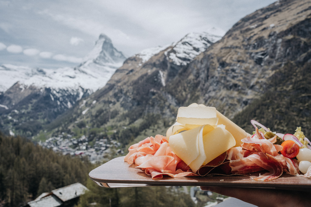 Winterwandern in der Schweiz mit Brotplatte, bestückt mit Schinken und Käse bei bestem Sonnenschein und Blick auf das Matterhorn