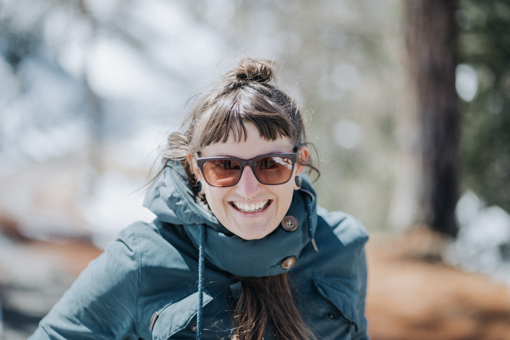 Lisa Ludwig lacht und geht gern Winterwandern in der Schweiz mit Sonnenbrille während die Sonne scheint