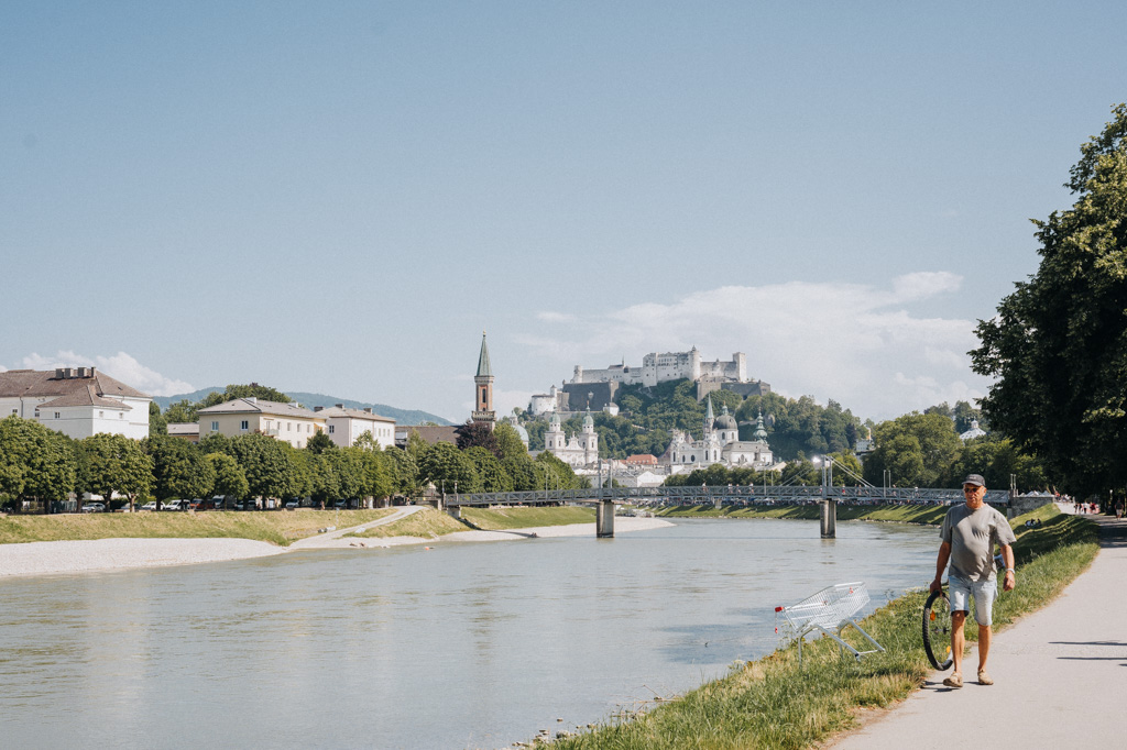 Spaziergang mit Hund entlang der Salzach mit Blick auf die Festung Hohensalzburg