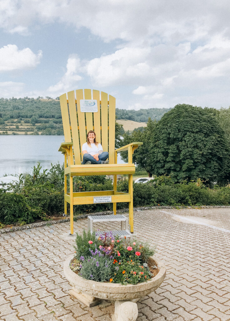Lisa Ludwig sitzt auf dem gelben Stuhl am Schalkenmehrener Maar Vulkaneifel