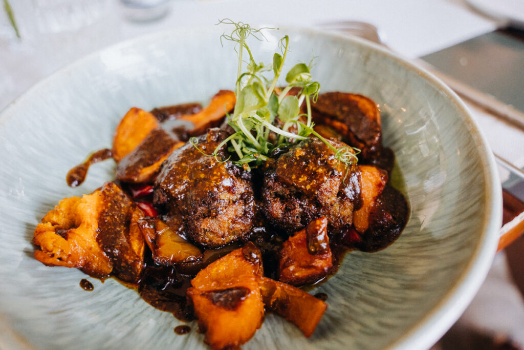 Hauptgericht Kalbsfrikadellen / Paprika / Rote Zwiebeln / Süsskartoffeln / Cashew / Senf-Jus im Restaurant interior no 253, essen gehen am Rhein